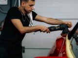 Man poetst een rode auto in een garage