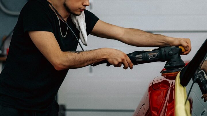 Man poetst een rode auto in een garage